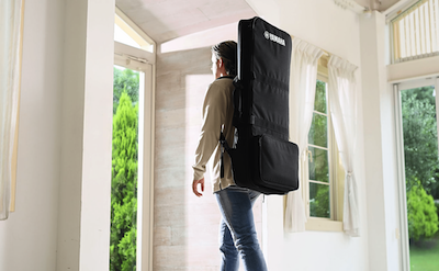 Photo of a person walking with the SC-KB650 keyboard bag for Yamaha Arranger Workstation PSR-SX series and PSR-E400 series on his back.