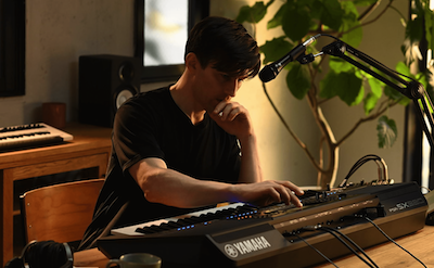 Photo of a person playing the Yamaha Arranger Workstation PSR-SX920 in a room with headphones on.